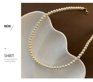 Détail d'un collier de perles blanches avec fermoir doré sur assiette décorative