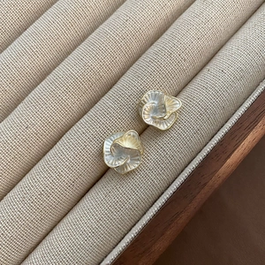 Elegant pearl white camellia flower stud earrings with gold trim on beige display stand