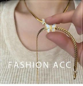 Close-up of golden Cuban chain necklace featuring elegant white shell butterfly pendants