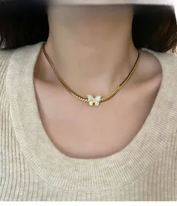 Detail of white butterfly pendant on a gold flat snake chain necklace worn by model