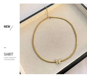 Close-up of gold snake chain necklace with white butterfly pendant in a jewelry box