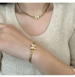 Detail view of gold butterfly pendant on flat snake chain worn by a model