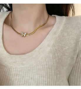 Flat gold snake chain necklace with white mother of pearl butterfly pendant on a model