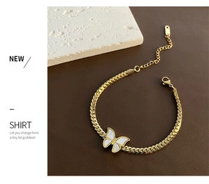 Detail view of a gold chain bracelet with a white butterfly pendant and lobster clasp
