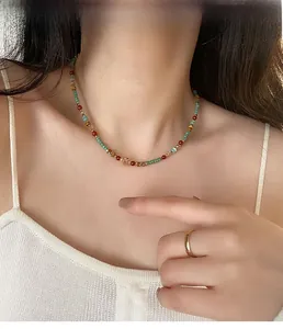 Gros plan du collier ethnique en perles avec pierres naturelles vertes et rouges sur modèle