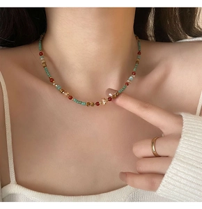 Détail d'un collier bohème en perles de pierre naturelle aux accents rétro vert et rouge