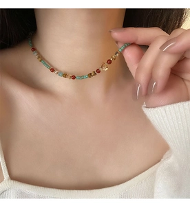 Détail d'un collier ethnique perlé avec pierres vert menthe et ambre sur un mannequin