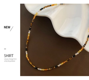 Detail of faceted tiger eye bead necklace with gold spacers on white ceramic tray