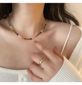 Detailed macro view of 2-3mm tiger eye beaded necklace on model's collarbone