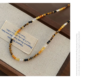 Detailed view of bohemian tiger eye beaded necklace with faceted crystals on linen fabric