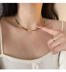 Detail of tiger eye bead necklace on model with golden metal spacers and multi-color beads