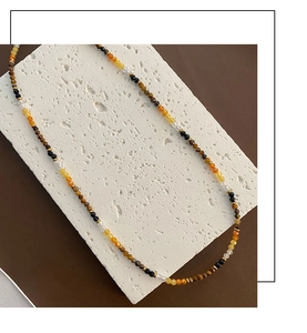 Close-up of multicolor tiger eye bead necklace with gold spacers on stone background