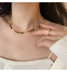 Detail of tiger eye beaded necklace with colorful stones and gold ring on neck