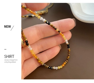 Detailed close-up of tiger eye and obsidian beaded necklace with metallic lobster clasp