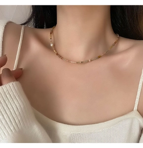 Détail de perles de pierres fines colorées et d'une perle blanche sur un collier