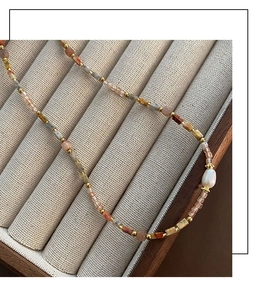 Détail macro d'un collier de perles en pierres précieuses et perle baroque sur écrin