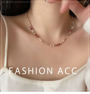 Close-up of handmade beaded necklace with red and gold beads on model collarbone