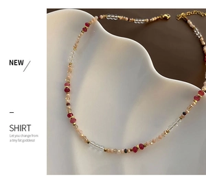 Detail of beaded necklace with faceted crystal beads and gold lobster clasp on a white plate