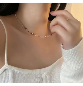 Close-up of elegant asymmetric beaded necklace with pink and white beads on a model