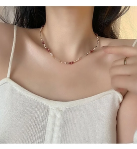 Close-up of elegant beaded necklace featuring red beads, white pearls, and gold accents