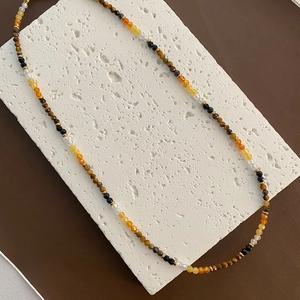 Tiger eye stone beaded necklace with multi-color beads and gold spacers on stone display