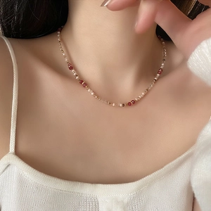 Elegant beaded necklace with red and white pearls shown on a model's neck