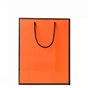 Elegant orange gift bag with black trim and woven handles for Mother's Day packaging