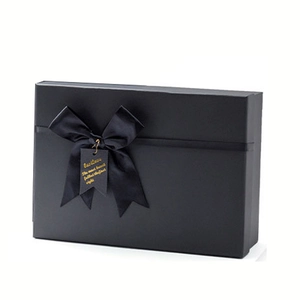 Premium matte black gift box with a satin ribbon bow and gold lettering tag detail