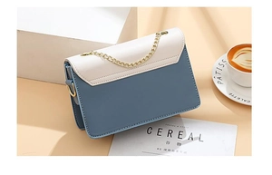 Elegante hellblaue und cremefarbene Umhängetasche mit goldener Kette in edlem Lifestyle-Ambiente