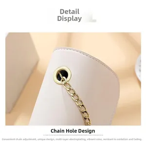 Detail der goldenen Kettenöse auf einer weißen, luxuriös bestickten Handtasche
