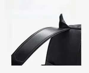 Close-up of wide leather handle with precise stitching on black nylon backpack