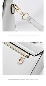 Detail of gold metal buckle and smooth rear zipper pocket on white leather handbag
