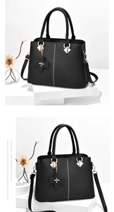 Close-up of black leather handbag with red and white polka dot stripe and golden hardware