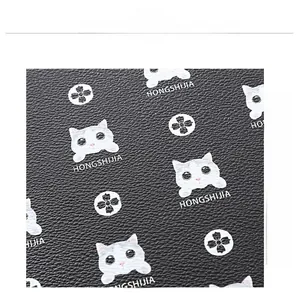 Close-up of black lychee grain leather featuring white cat head and floral pattern prints