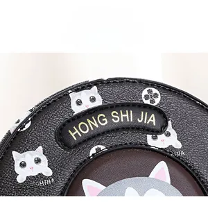 Macro shot of black lychee-textured leather bag with gold-stamped cat-themed details