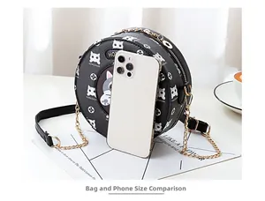 Compact black round crossbody bag with white cat illustration compared next to a phone