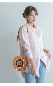 Detail of round crossbody bag with cute cat pattern and brown lychee grain leather finish