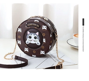 Close-up of a brown round crossbody bag featuring cat patterns and gold chain strap