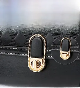 Detail of black quilted handbag featuring a golden oval twist lock with woven metal trim