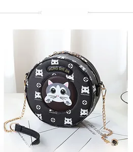Detail of round black crossbody bag featuring cartoon cat prints and gold chain strap
