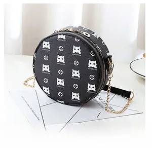 Detailed view of round crossbody bag with white cat print and gold chain strap