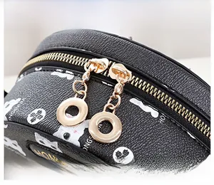 Detail of golden metal zippers on textured black leather cat print crossbody bag