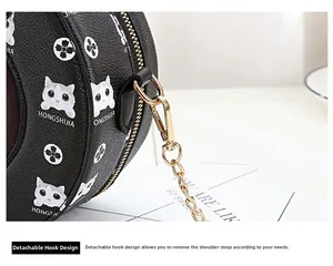 Detail of detachable gold metal hook and black pebble leather on cartoon cat round bag