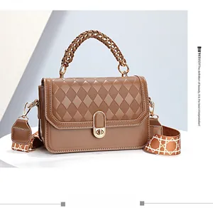 Macro detail of brown quilted leather handbag with gold clasp and geometric wide strap