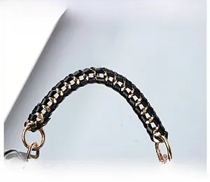 Detail of woven black leather and golden metal chain handle on a stylish handbag