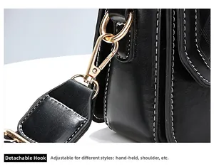 Detail of the detachable gold-tone hook and white stitching on the black leather handbag