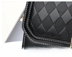 Detailed view of black leather handbag with rhombus quilting and white contrast stitching