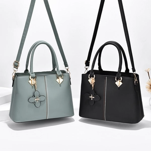 Women's minimalist leather handbag in mint green and black with clover pendant