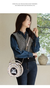 Detail of round crossbody bag with cat pattern, handheld by model in denim