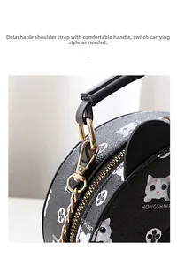 Detail of round crossbody bag with black lychee leather texture and cat pattern